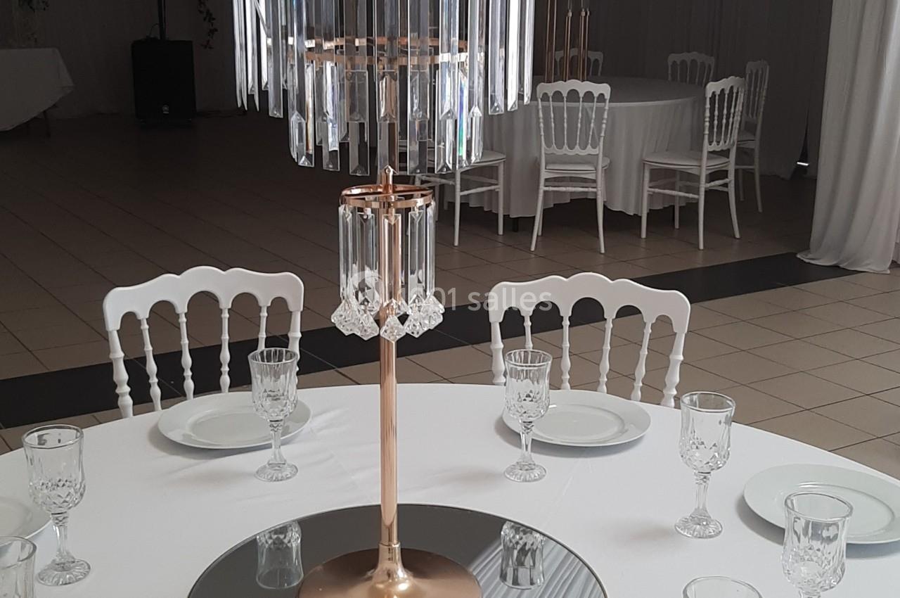 Centre de table élégant avec des roses blanches et des pampilles en cristal, entouré de vaisselle sur une nappe blanche.