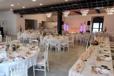 Cuisine professionnelle avec évier en inox, lave-vaisselle industriel, chariots noirs et casiers empilés sur sol carrelé.