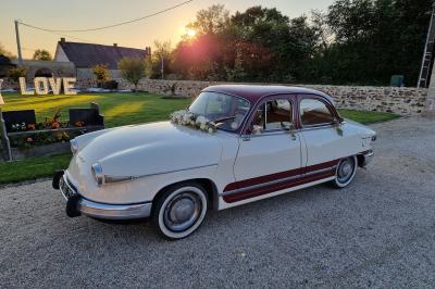 Cuisine professionnelle avec évier en inox, lave-vaisselle industriel, chariots noirs et casiers empilés sur sol carrelé.