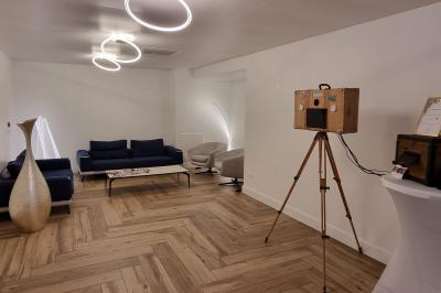 Cuisine professionnelle avec évier en inox, lave-vaisselle industriel, chariots noirs et casiers empilés sur sol carrelé.