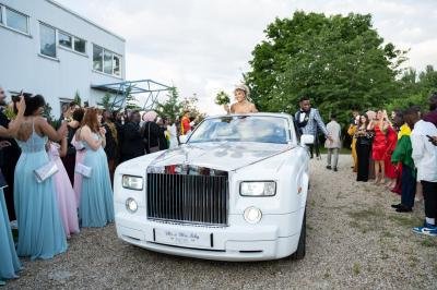 Façade d'un bâtiment moderne éclairé de nuit, avec des plantes et un panneau ’La Scène’ visible.