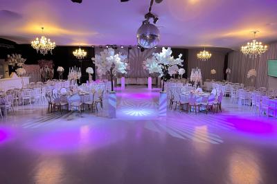 Façade d'un bâtiment moderne éclairé de nuit, avec des plantes et un panneau ’La Scène’ visible.