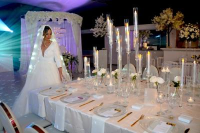 Façade d'un bâtiment moderne éclairé de nuit, avec des plantes et un panneau ’La Scène’ visible.