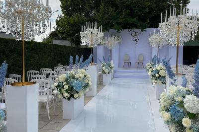 Façade d'un bâtiment moderne éclairé de nuit, avec des plantes et un panneau ’La Scène’ visible.