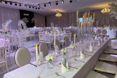 Façade d'un bâtiment moderne éclairé de nuit, avec des plantes et un panneau ’La Scène’ visible.