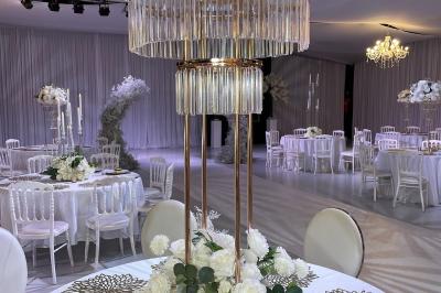 Façade d'un bâtiment moderne éclairé de nuit, avec des plantes et un panneau ’La Scène’ visible.