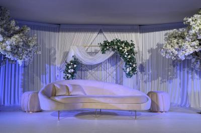 Façade d'un bâtiment moderne éclairé de nuit, avec des plantes et un panneau ’La Scène’ visible.