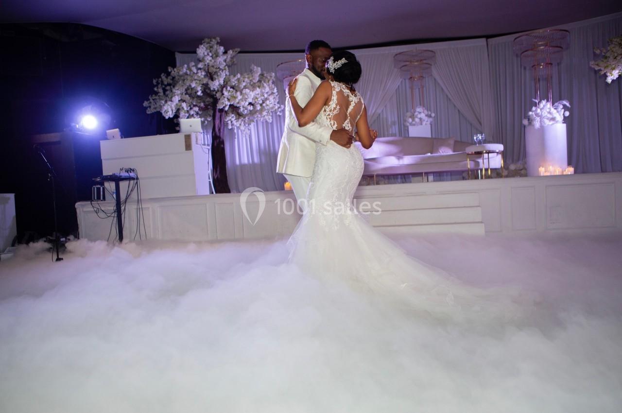 Un couple danse dans une salle décorée de blanc avec un sol recouvert d'un effet de fumée.