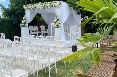 Façade d'un bâtiment moderne éclairé de nuit, avec des plantes et un panneau ’La Scène’ visible.
