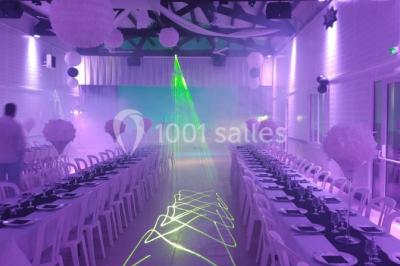 Bâtisse provençale entourée de cyprès et de champs verts, avec des arbres en arrière-plan sous un ciel clair.