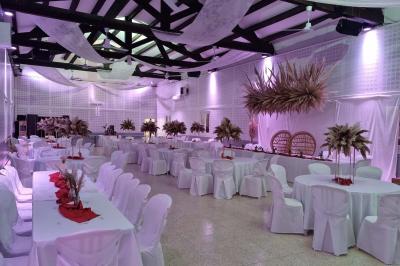 Bâtisse provençale entourée de cyprès et de champs verts, avec des arbres en arrière-plan sous un ciel clair.