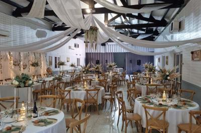 Bâtisse provençale entourée de cyprès et de champs verts, avec des arbres en arrière-plan sous un ciel clair.