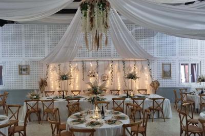 Bâtisse provençale entourée de cyprès et de champs verts, avec des arbres en arrière-plan sous un ciel clair.