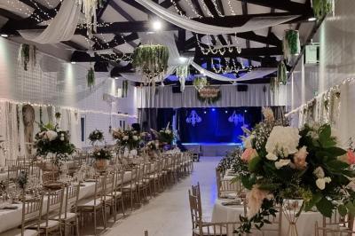 Bâtisse provençale entourée de cyprès et de champs verts, avec des arbres en arrière-plan sous un ciel clair.
