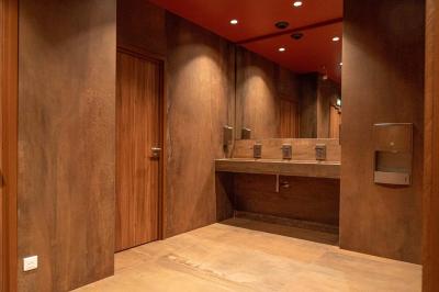 Salle de bain moderne avec murs et sols en finition bois, lavabo collectif et éclairage encastré.