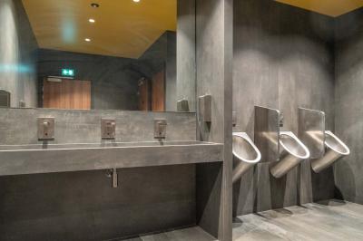 Salle de bain moderne avec murs et sols en finition bois, lavabo collectif et éclairage encastré.