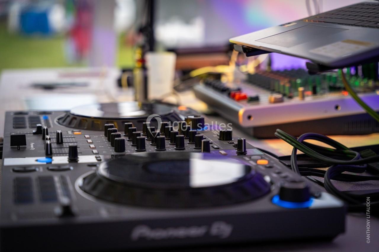 Table de mixage DJ avec platines et contrôles, connectée à un ordinateur portable et des équipements audio.