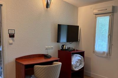 Viande en cuisson sur une broche au-dessus d'un barbecue en plein air, dans un jardin verdoyant.