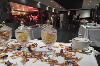 Viande en cuisson sur une broche au-dessus d'un barbecue en plein air, dans un jardin verdoyant.
