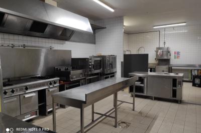 Viande en cuisson sur une broche au-dessus d'un barbecue en plein air, dans un jardin verdoyant.