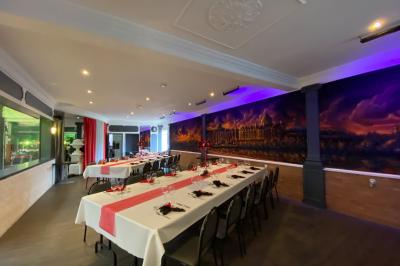 Viande en cuisson sur une broche au-dessus d'un barbecue en plein air, dans un jardin verdoyant.