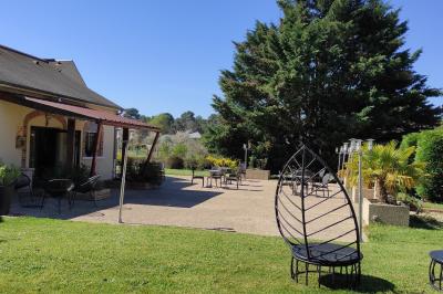Viande en cuisson sur une broche au-dessus d'un barbecue en plein air, dans un jardin verdoyant.