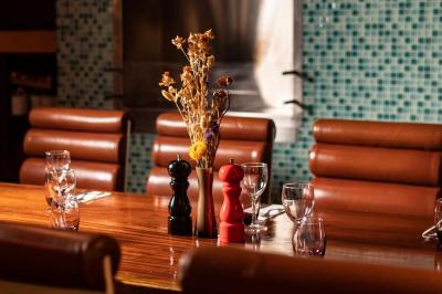 Salle de restaurant avec des tables dressées, des chaises en cuir marron et une enseigne murale ’LA CASA’.