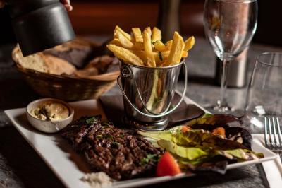 Salle de restaurant avec des tables dressées, des chaises en cuir marron et une enseigne murale ’LA CASA’.