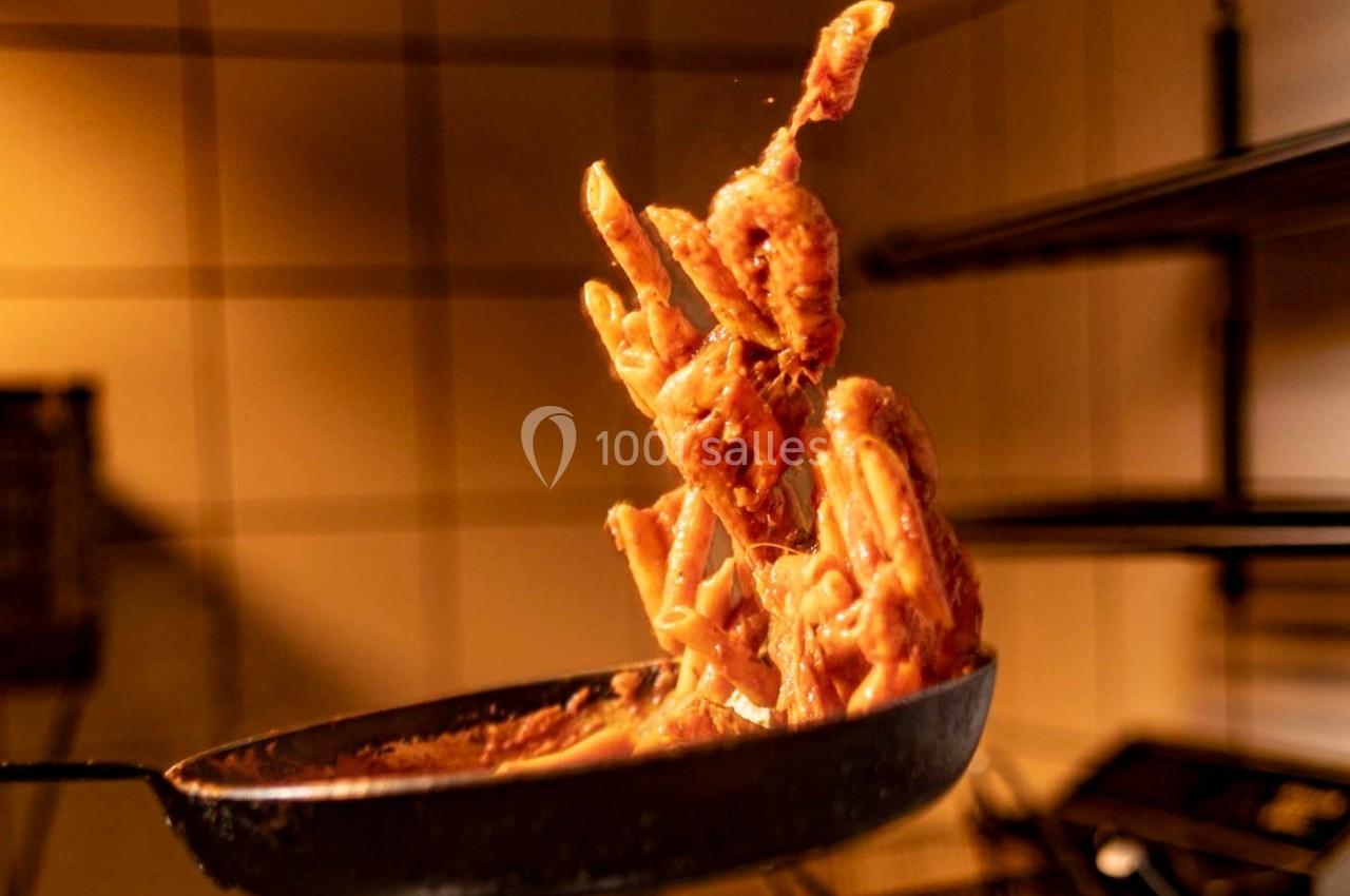 Des morceaux de viande en sauce sautés dans une poêle, capturés en plein mouvement dans une cuisine.