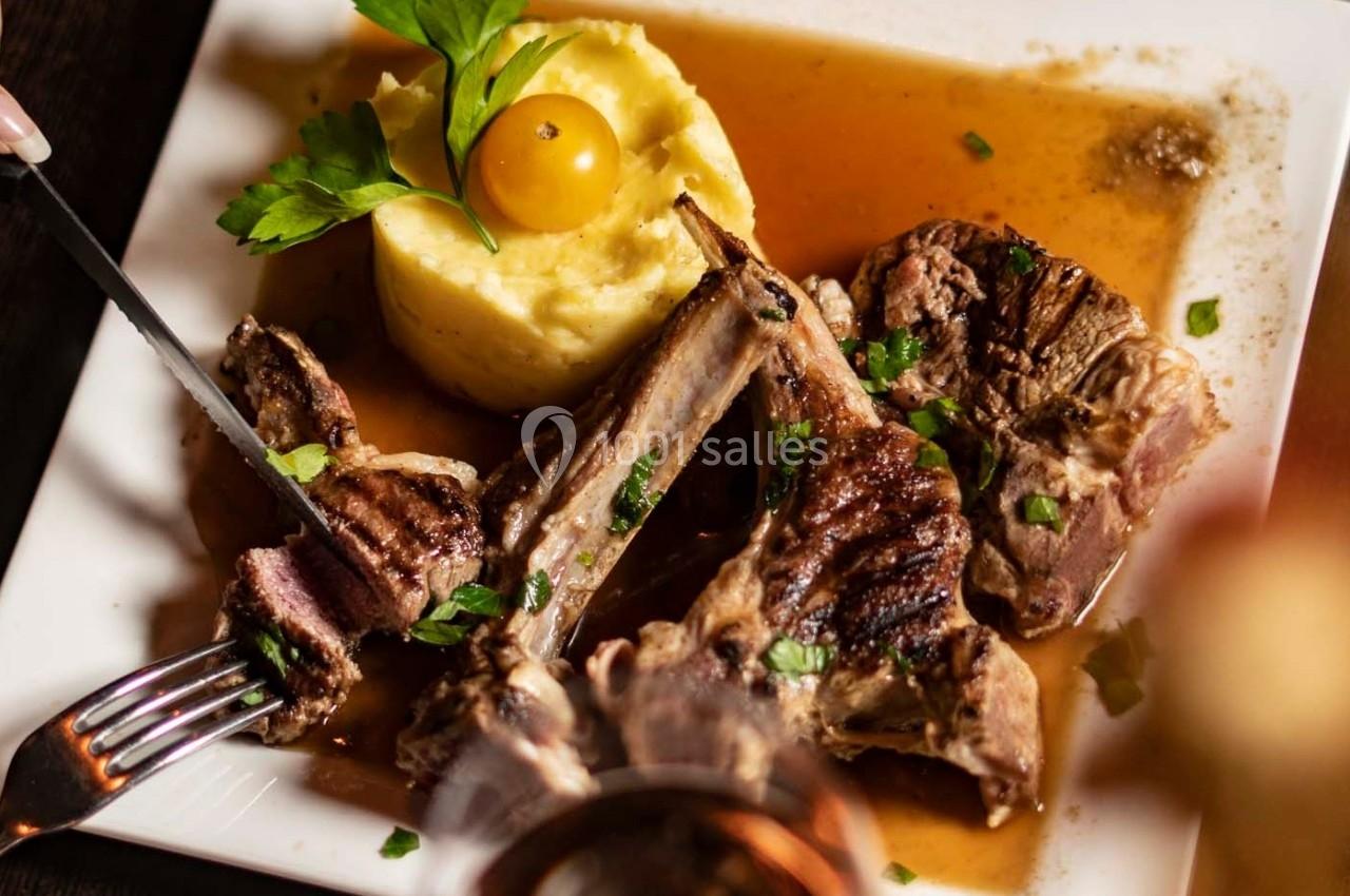 Assiette de côtelettes d'agneau grillées avec purée de pommes de terre, sauce et garniture de persil et tomate cerise.