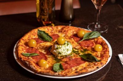 Salle de restaurant avec des tables dressées, des chaises en cuir marron et une enseigne murale ’LA CASA’.