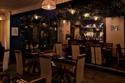 Salle de restaurant avec des tables dressées, des chaises en cuir marron et une enseigne murale ’LA CASA’.