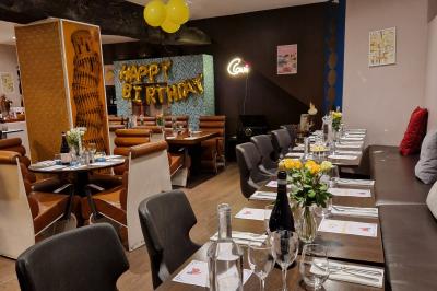 Salle de restaurant avec des tables dressées, des chaises en cuir marron et une enseigne murale ’LA CASA’.