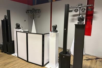 Équipement de sonorisation et d'éclairage installé dans une salle, comprenant enceintes, projecteurs et panneaux blancs.