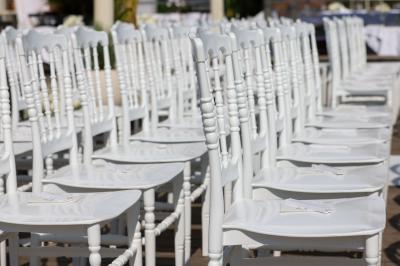 Rangées de chaises blanches alignées en extérieur, probablement pour un événement ou une cérémonie.