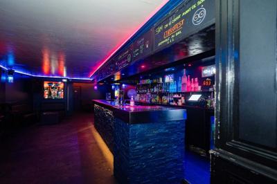 Vue intérieure d'une cellule ancienne avec murs en pierre, bancs en bois et éclairage rose.