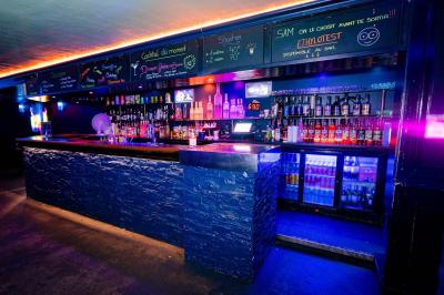 Vue intérieure d'une cellule ancienne avec murs en pierre, bancs en bois et éclairage rose.