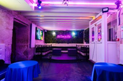 Vue intérieure d'une cellule ancienne avec murs en pierre, bancs en bois et éclairage rose.