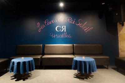 Vue intérieure d'une cellule ancienne avec murs en pierre, bancs en bois et éclairage rose.