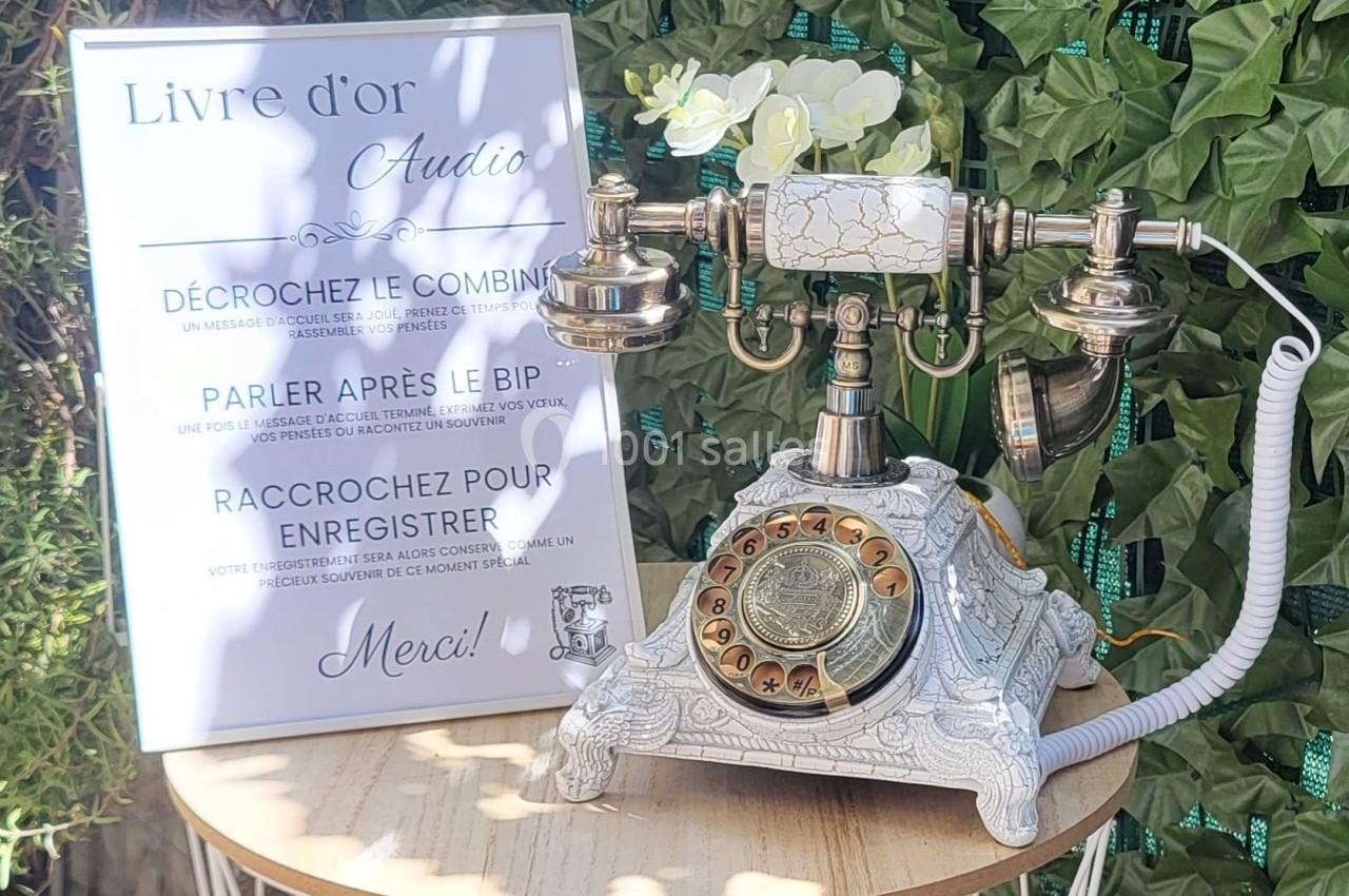 Téléphone rétro décoratif avec cadran doré, posé près d'un panneau expliquant son usage comme livre d'or audio.