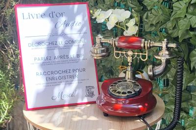 Photo d'un téléphone rouge rétro, un disque vinyle noir, un disque rouge en forme de cœur et une photo de mariage.
