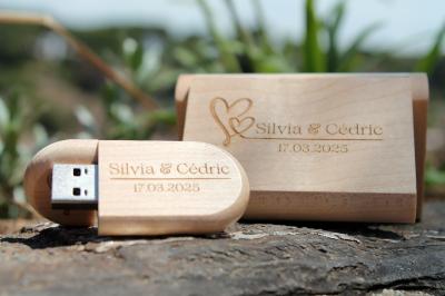 Clé USB en bois gravée ’Voice Memories’ avec son étui assorti, posée sur une surface naturelle.