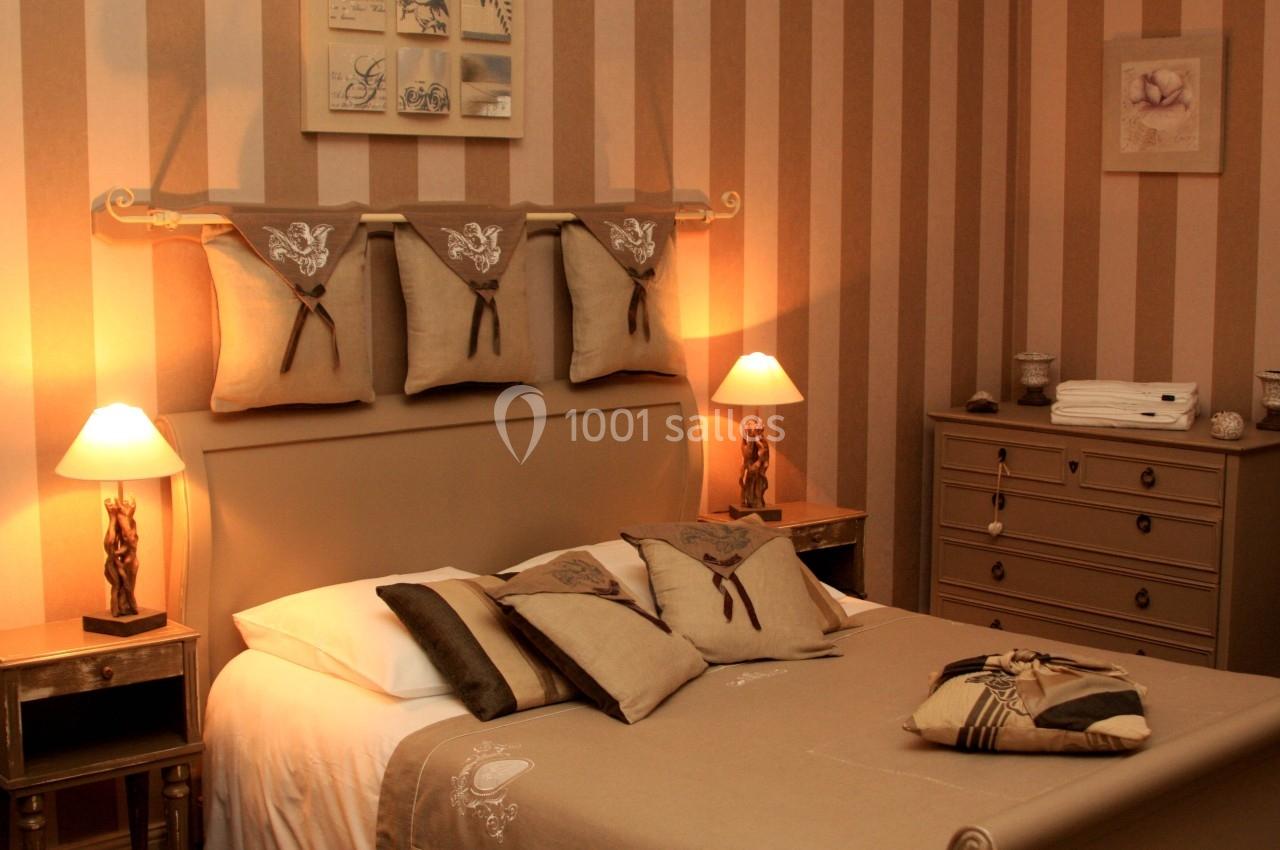 Chambre décorée dans des tons beige et marron avec lit double, lampes de chevet et commode assortie.