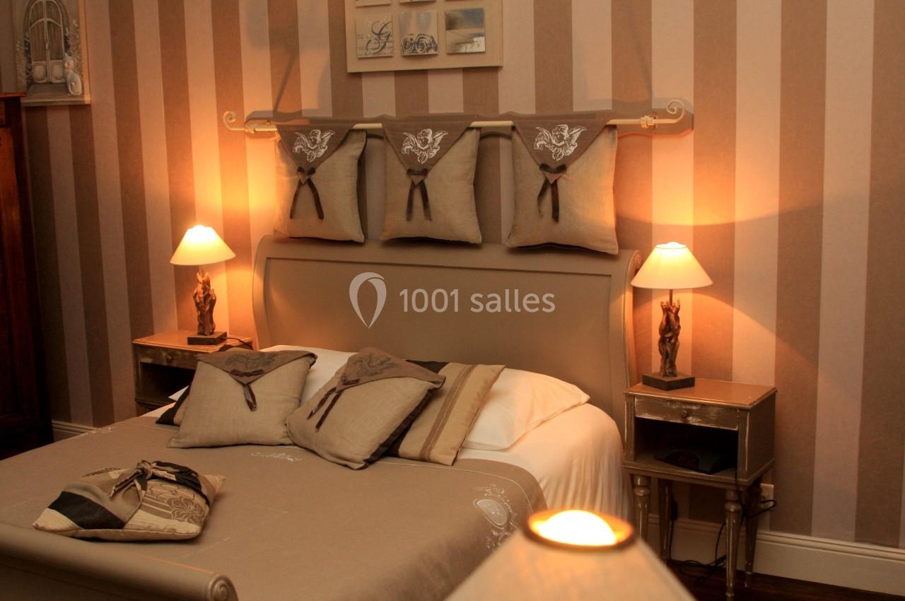 Chambre avec lit double, décorée dans des tons beige et marron, éclairée par des lampes de chevet.