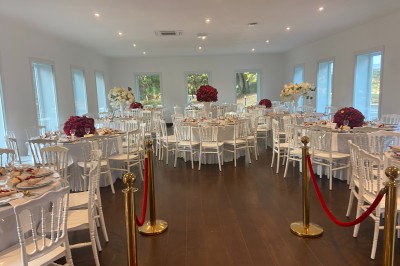 Décoration de table de réception avec nappes blanches, chandeliers, vaisselle élégante et arrangement floral blanc.