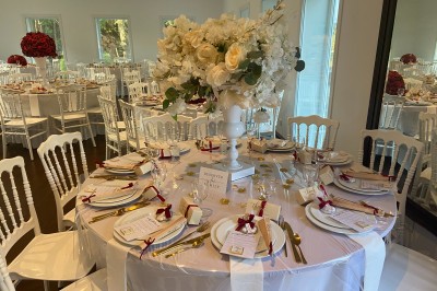 Décoration de table de réception avec nappes blanches, chandeliers, vaisselle élégante et arrangement floral blanc.