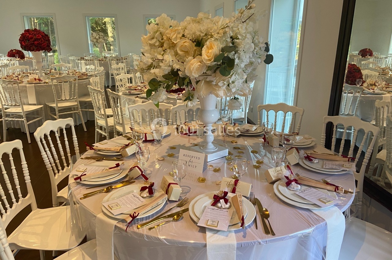 Table élégamment dressée pour un événement, avec des fleurs blanches en centre de table et des couverts dorés.