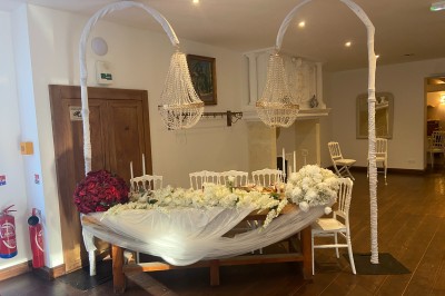Décoration de table de réception avec nappes blanches, chandeliers, vaisselle élégante et arrangement floral blanc.