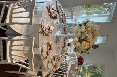 Décoration de table de réception avec nappes blanches, chandeliers, vaisselle élégante et arrangement floral blanc.