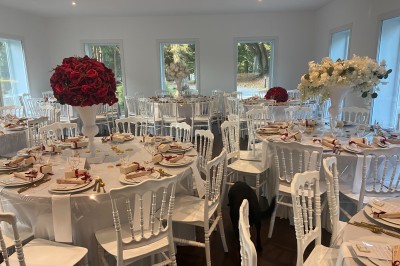 Décoration de table de réception avec nappes blanches, chandeliers, vaisselle élégante et arrangement floral blanc.